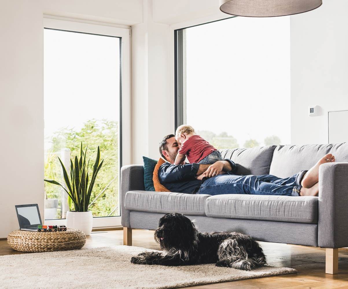 father plays with toddler on couch