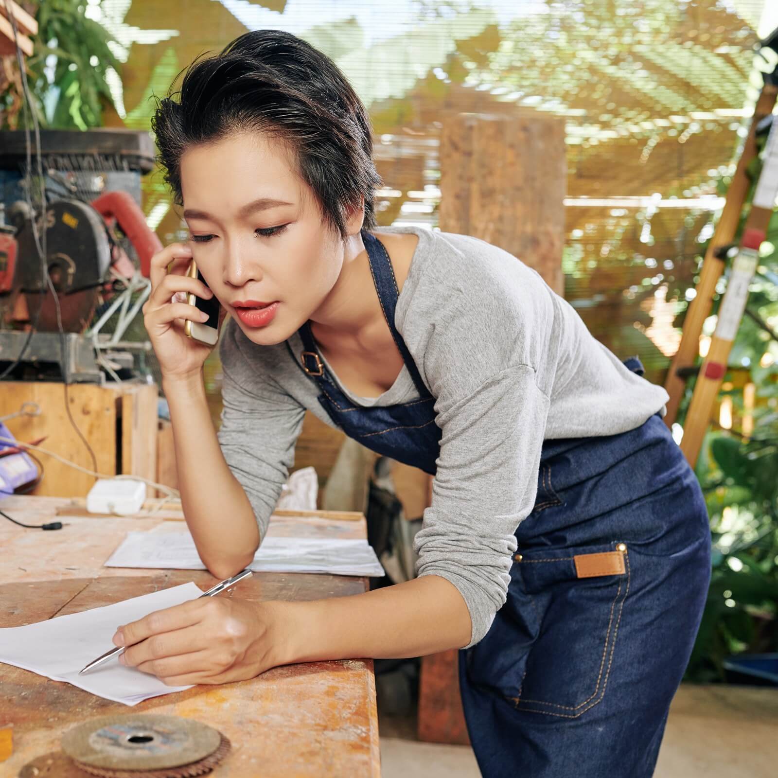 woman talking on phone while writing on paper